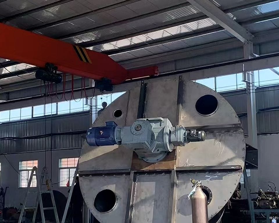 Modified cycloidal gearmotor mounted through the bottom head of an unpainted conical screw mixer shell, in the assembly bay